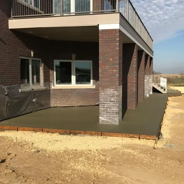New concrete patio under a brick house with a balcony.