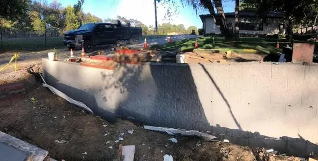 Construction site with a concrete wall, a black pickup truck, and orange traffic cones.