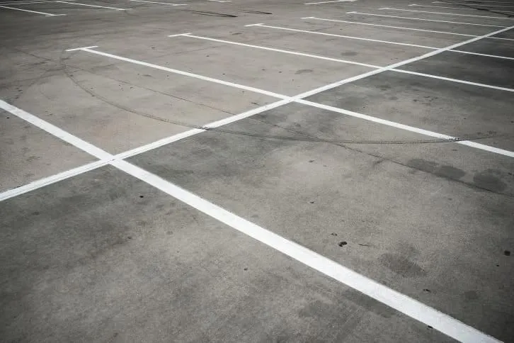 Empty parking lot with white painted lines on gray concrete.