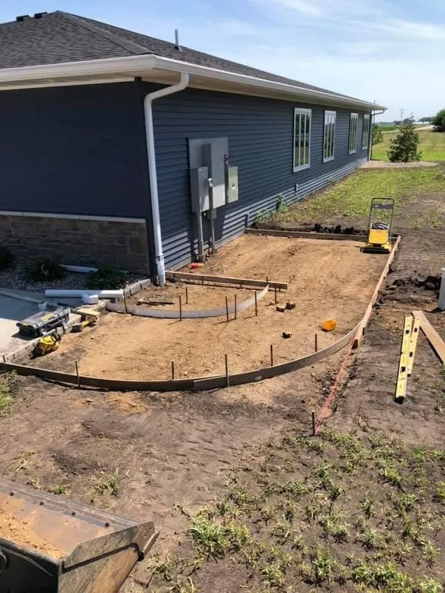 Workers smoothing wet concrete for a sidewalk with hand tools in an outdoor setting.