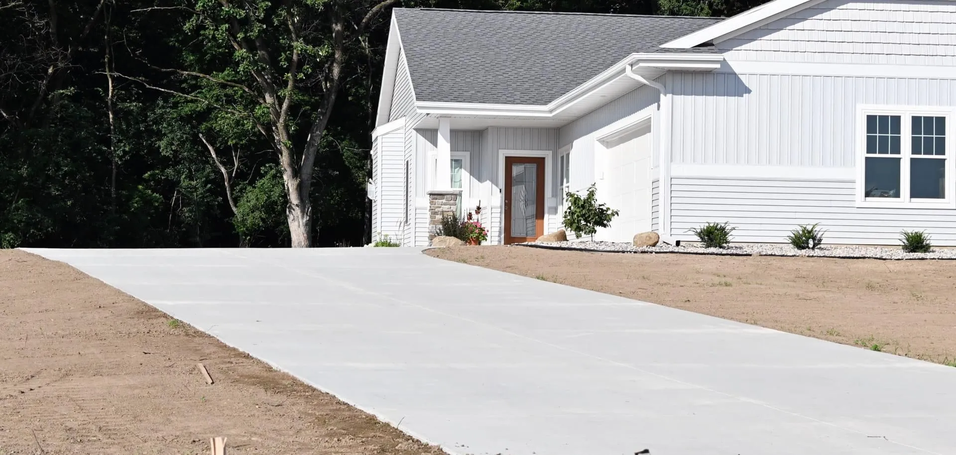 Newly poured concrete driveway leading up to a white ranch house
