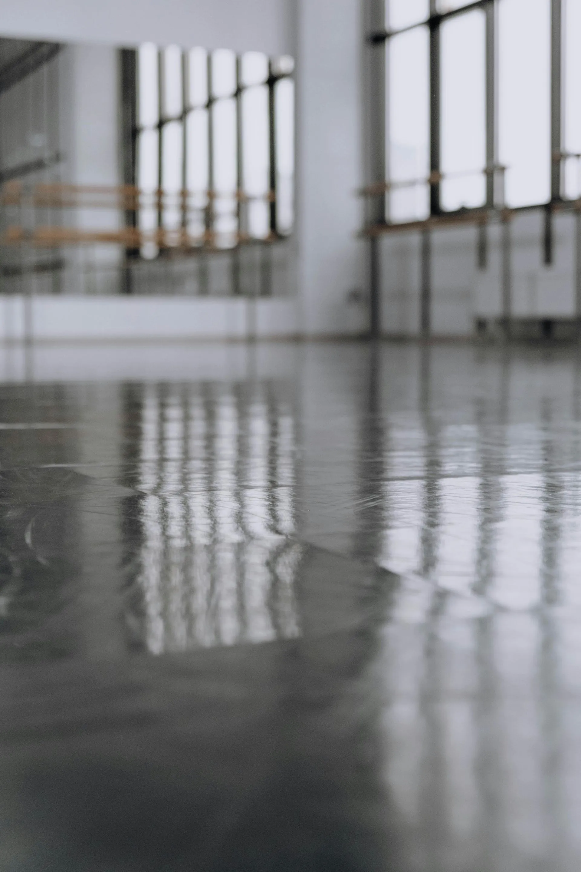 Close-up of a reflective polished concrete floor beside tall industrial windows