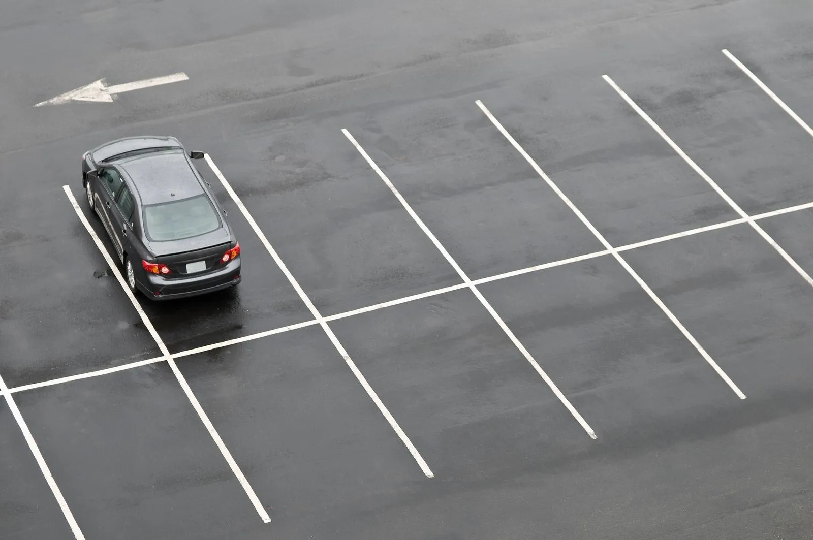 Single car parked in a freshly striped, empty parking lot