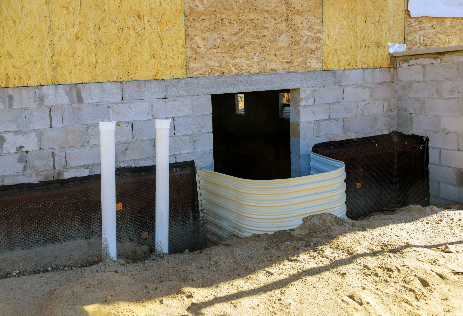 Workers smoothing wet concrete for a sidewalk with hand tools in an outdoor setting.